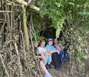 Dzieci budujące szałas podczas warsztatów survivalowych w lesie przy Zagrodzie na Wzgórzu