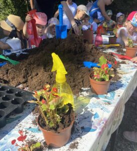 Dziecko sadzące roślinę podczas warsztatów ogrodniczych w Zagrodzie na Wzgórzu